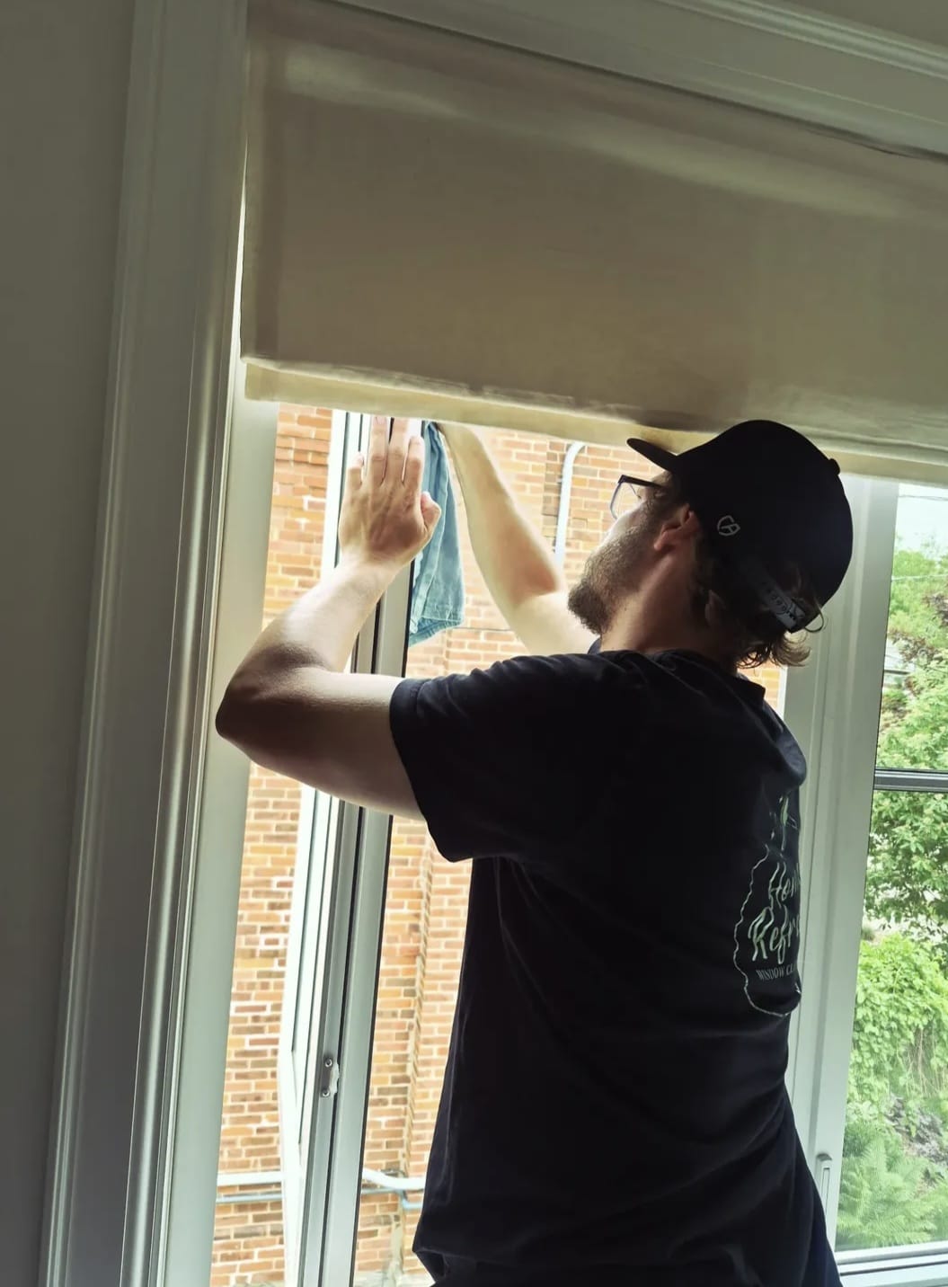Window cleaning technician detailing an interior window